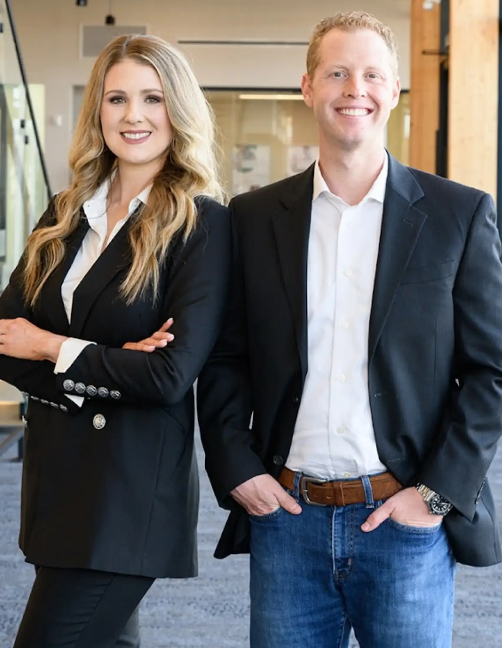 owners Two professionals in smart attire posing for a photo indoors.